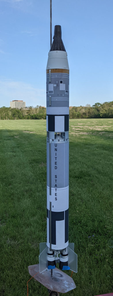 A scale model of a Gemini-Titan rocket, on a model rocket launch pad in a park.